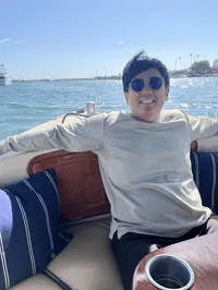 Jeffrey Ren smiling sitting on a boat with an ocean background